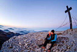 Two hikers at summit of Hochschwab mountain at sunrise, Hochschwab, Styria, Austria