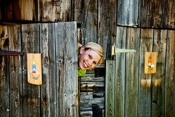 Young woman behind a ladies' room door looking at camera, lake Duisitzkar, Styria, Austria