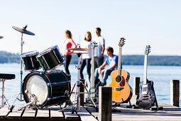 Musical instruments on a jetty at lake Starnberg, four persons in background, Bavaria, Germany