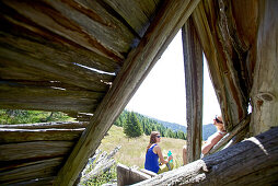 Zwei Wanderinnen rasten vor den Überresten einer Holzhütte, Nockberge, Kärnten, Österreich
