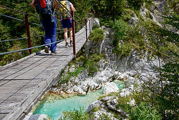 Zwei Wanderinnen gehen auf einer Holzbrücke über den Fluss Soca, Alpe-Adria-Trail, Tolmin, Slowenien