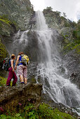 Two female hikers looking at a waterfall, Nockberge, Carinthia, Austria