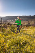 Junge Frau wandert über einen Weinberg, Val d Orcia, Toskana, Italien