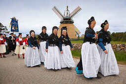 Women in traditional frisian costumes, in front of a windmill, Nebel, Amrum island, North Sea, North Friesland, Schleswig-Holstein, Germany