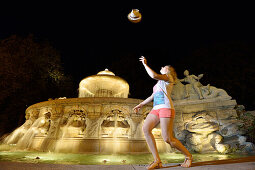 Young woman in front of fountain Wittelsbacherbrunnen at night, Lenbachplatz, Upper Bavaria, Bavaria, Germany
