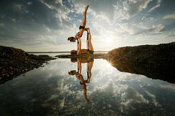 Couple practicing acroyoga at lake Starnberg, Upper Bavaria, Germany