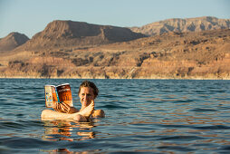 Woman reading a guidebook in Dead Sea, Jordan, Middle East