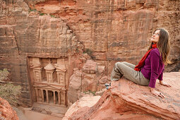Frau sitzt auf einem Felsen, Khazne al-Firaun im Hintergrund, Petra, Jordanien, Naher Osten