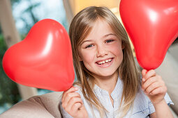 Girl holding two heart-shaped balloons, Hamburg, Germany