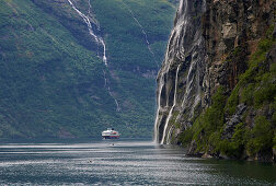 Wasserfall, Die Sieben Schwestern, und Hurtigruten im Geirangerfjord, Provinz Möre og Romsdal, Vestlandet, Norwegen, Europa