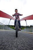 Man riding an electric bicycle passing a bridge, Tanna, Thuringia, Germany