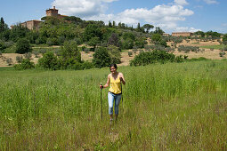 Woman nordic walking through a field at the foot of the Vinery Palazzo Massani, near San Quirico d'Orcia, Toskana, Italy, Europe