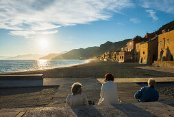 Personen betrachten Sonnenuntergang am Strand, Varigotti, Finale Ligure, Provinz Savona, Ligurien, Italien