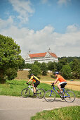 Two cyclists, castle Mochental in background, Ehingen, Baden-Wuerttemberg, Germany