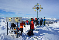 Back-country skiers beside a summit cross with signs of world religions, Kleiner Gilfert, Tux Alps, Tyrol, Austria