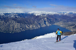 Frau auf Skitour steigt zum Monte Baldo auf, Gardasee im Hintergrund, Monte Baldo, Gardaseeberge, Trentino, Italien