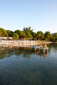 Couple on a pier at a hotel beach, Vourvourou, Sithonia, Chalkidiki, Greece
