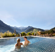 Couple in a hotel outdoor pool, Engstligenalp and Wildstrubel in background, Adelboden, Canton of Bern, Switzerland