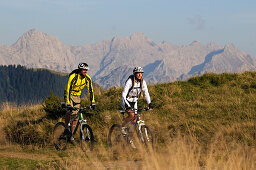 Mountain bikers passing Winklmoosalm, Berchtesgaden Alps in background, Chiemgau, Upper Bavaria, Germany