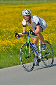 Young woman riding a racing bicycle, Upper Bavaria, Germany