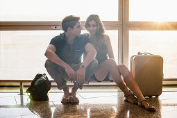 Young couple sitting on railing in airport