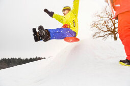 Boy sledging over bump in snow