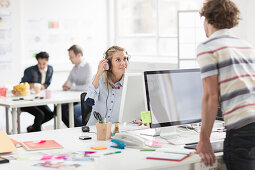 Young man looking at woman over monitor in creative office