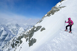 Female back-country skier standing in notch between Piz Zuort and Piz da la Crappa, Piz Zuort, Sesvenna Alps, Engadin, Graubuenden, Switzerland