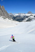 Frau auf Skitour fährt vom Corno d'Angolo ab, Drei Zinnen im Hintergrund, Cristallo, Dolomiten, Venetien, Italien