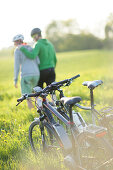 Two cyclists with E-bikes resting in a flower meadow, Munsing, Upper Bavaria, Germany