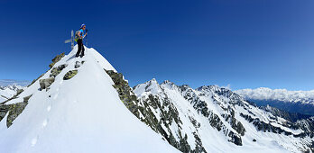 Skitourengeherin steht am Gipfel der Fünften Hornspitze, Hornspitzen und Schwarzenstein im Hintergrund, Zillertaler Alpen, Ahrntal, Südtirol, Italien