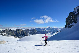 Female back-country skier ascending in Val Culea, Fanes range in background, Sella Group, Dolomites, South Tyrol, Italy