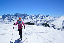 Female back-country skier ascending to Piz Lagrev, Bernina Range in background, Oberhalbstein Alps, Engadin, Canton of Graubuenden, Switzerland