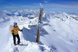 Frau auf Skitour steht am Gipfel des Großen Möseler, Hochfeiler im Hintergrund, Zillertaler Alpen, Südtirol, Italien