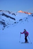 Frau auf Skitour steigt zum Großvenediger auf, Alpenglühen an der Schlieferspitze im Hintergrund, Venedigergruppe, Nationalpark Hohe Tauern, Salzburg, Österreich