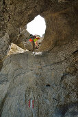 Female hiker descending through pierced rock, Schinderkar, Schinder, Bavarian Prealps, Upper Bavaria, Bavaria, Germany