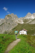 Woman hiking to hut Steinseehuette, Steinkarspitze in background, Lechtal Alps, Tyrol, Austria