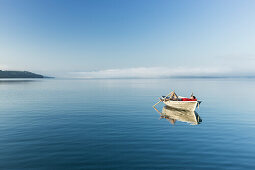 Man in a rowboat on lake Starnberg, the Alps and mount Zugspitze in early morning fog, Berg, Upper Bavaria, Germany