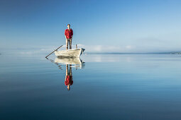Man in a rowboat on lake Starnberg, the Alps and mount Zugspitze in early morning fog, Berg, Upper Bavaria, Germany