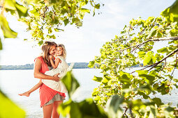 Mother carrying daughter in her arms, lake Starnberg, Berg, Upper Bavaria, Germany