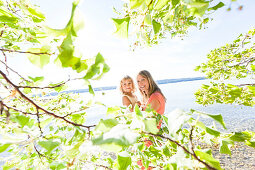 Mother carrying daughter in her arms, lake Starnberg, Berg, Upper Bavaria, Germany