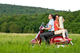 Ein Mann und eine Frau transportieren mit einem roten Vespa Roller einen Stapel Bücher, Odershausen, Bad Wildungen, Nordhessen, Hessen, Deutschland, Europa