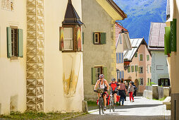 Radfahrer fahren über Kopfsteinpflaster, Guarda, Unterengadin, Engadin, Kanton Graubünden, Schweiz