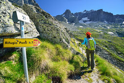 Woman hiking with marker in foreground, Sentiero Roma, Bergell range, Lombardy, Italy