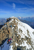 Several persons climbing on ridge to Gran Paradiso, Mont Blanc in background, Gran Paradiso, Gran Paradiso Nationalpark, Graian Alps range, valley of Aosta, Aosta, Italy