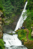 Mehrere Personen beim Canyoning stehen vor Wasserfall, Cavalese, Val di Fiemme, Fleimstal, Lagorai, Dolomiten, UNESCO Welterbe Dolomiten, Trentino, Italien