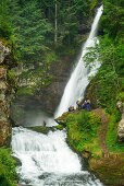 Serveral persons canyoning standing in front of a waterfall, Cavalese, valley Val di Fiemme, Lagorai range, Dolomites, UNESCO world heritage Dolomites, Trentino, Italy