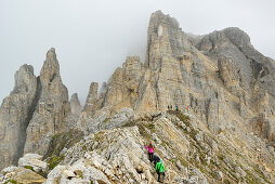 Persons hiking on rock ridge to Torre di Pisa, Latemar range, Dolomites, UNESCO world heritage Dolomites, Trentino, Italy