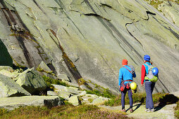 Zwei Personen mit Kletterausrüstung gehen auf Kletterfelsen zu, Azalee Beach, Grimselpass, Berner Oberland, Schweiz