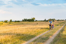 Cyclist with child trailer cycling along a coastal path, Marielyst, Falster, Denmark